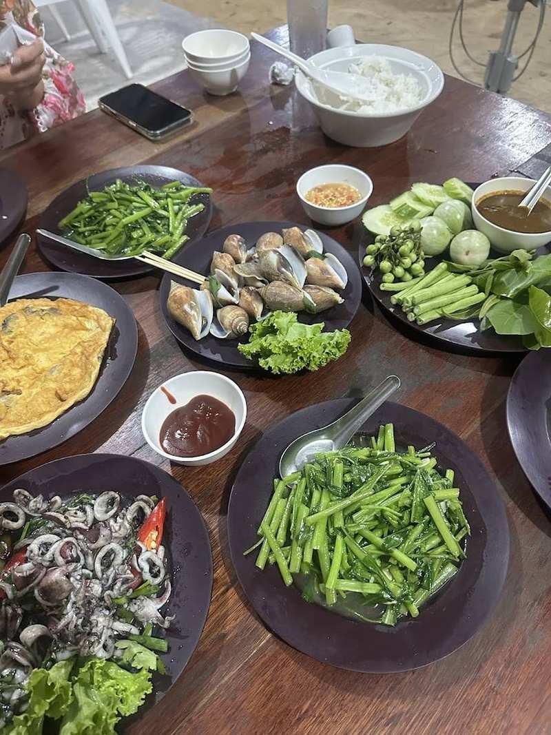 หอยชักตีน ไข่เจียว หมึก และผักผัดวางเต็มโต๊ะ